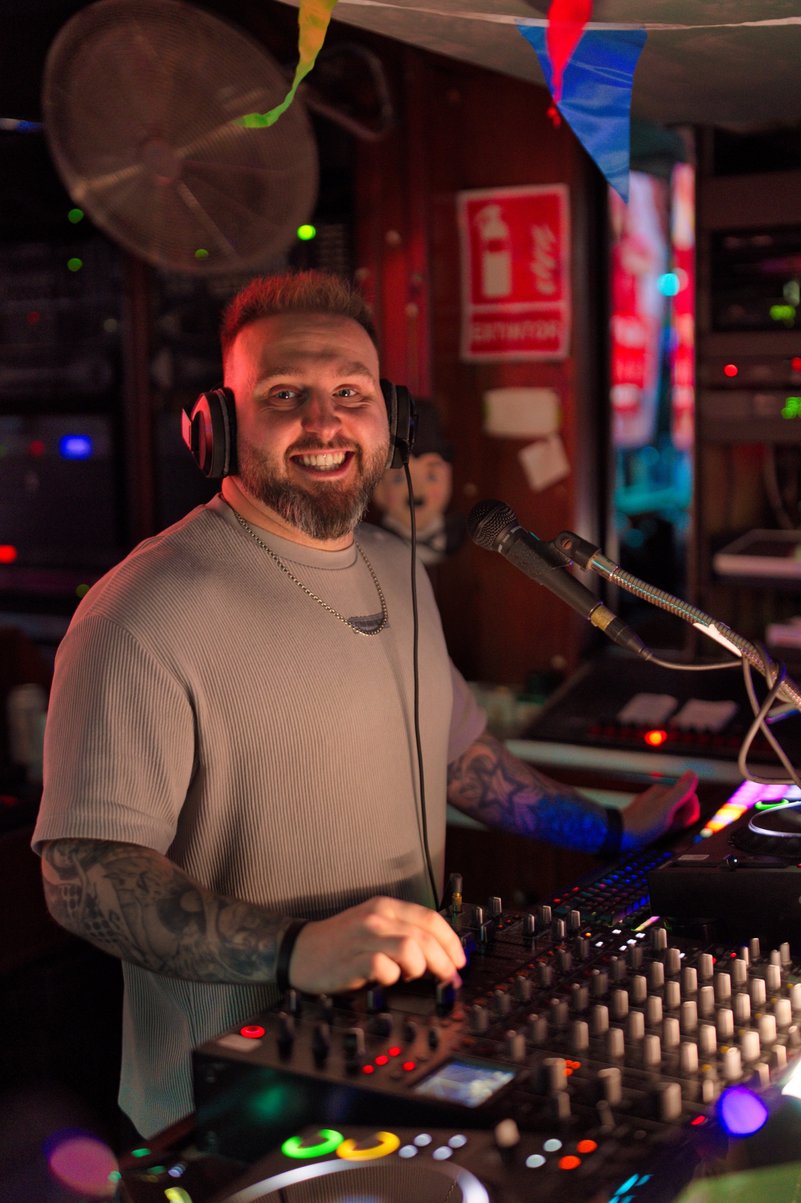 Ash Jenkins smiling behind a DJ booth